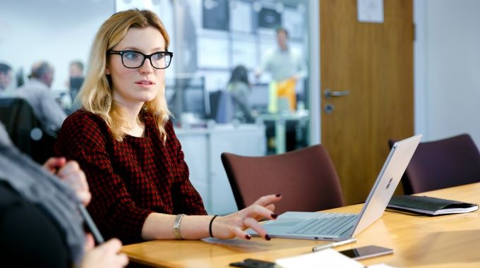 Woman using a laptop and talking with others during a meeting in a conference room