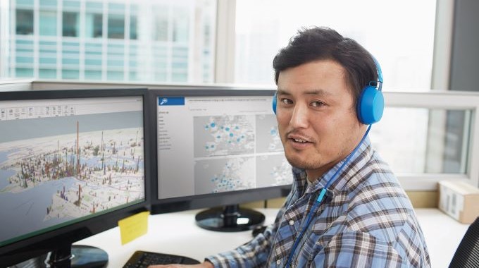 Man working on computer with blue headphones on.