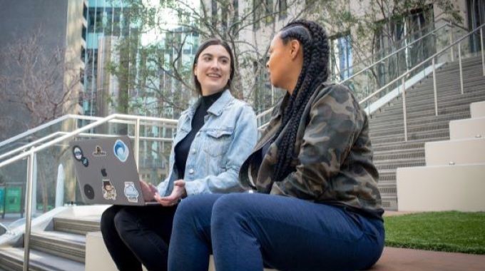 Real people. Close up of two female developers collaborating while working remotely. One developer has personalized her laptop with stickers.