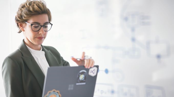 Engaged developer in context of white board session with colleagues, looking at laptop