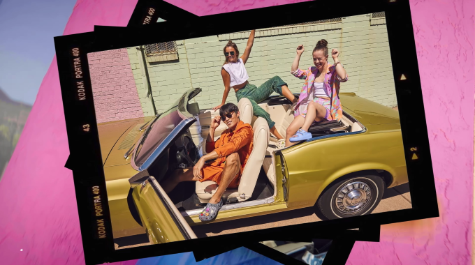3 people sitting in a yellow convertible wearing Crocs shoes