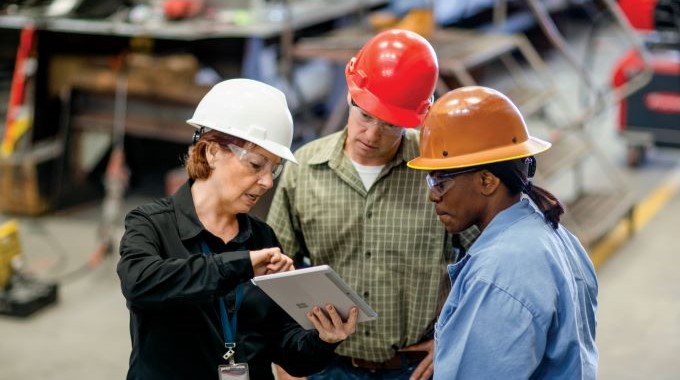 La directora general de una gran empresa manufacturera conversa sobre un proyecto con el jefe de operaciones y el capataz.